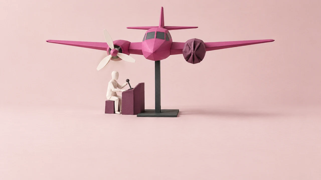 A magenta twin-engine aircraft on a test stand, one propeller wrapped and stopped, with an operator at a console below