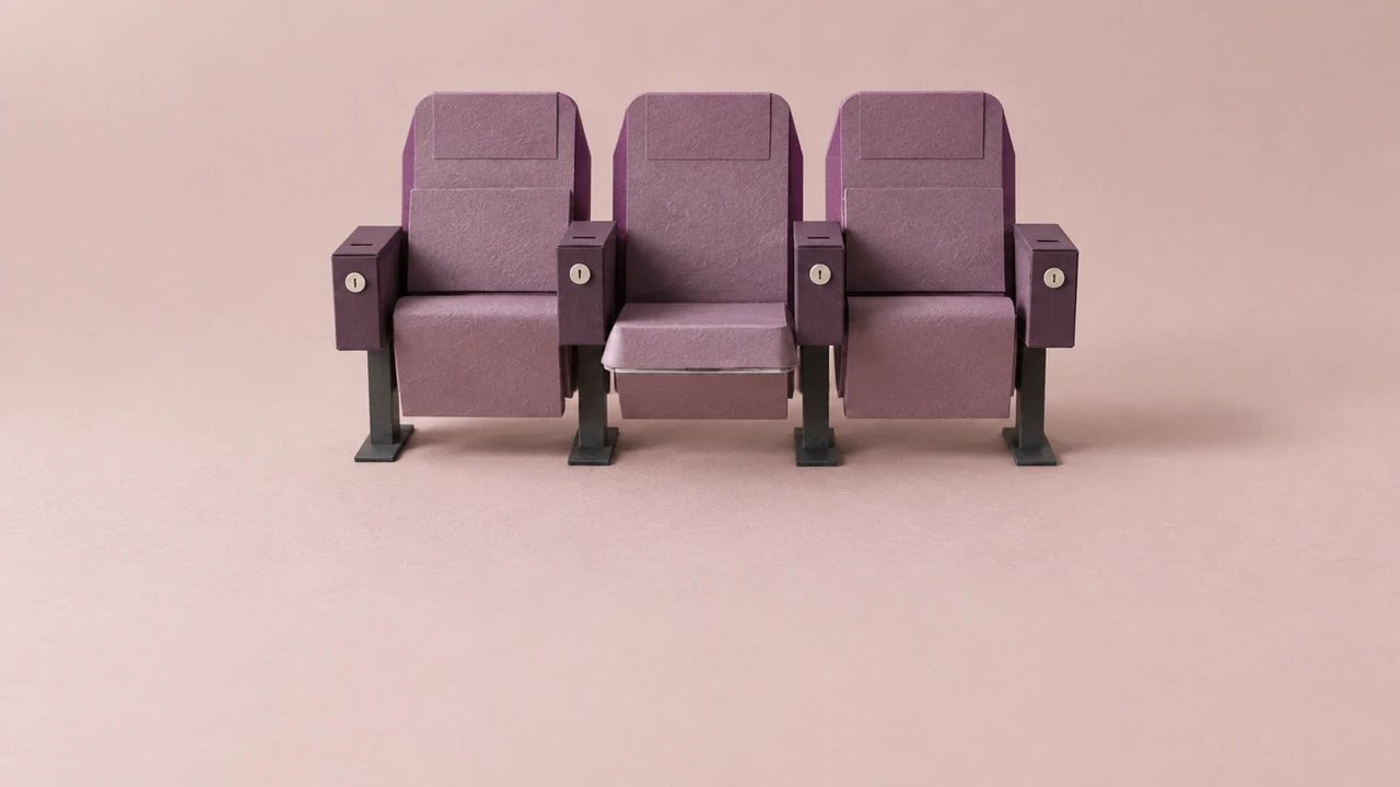 A row of three purple cinema seats, each armrest fitted with a small coin-operated box with a slot