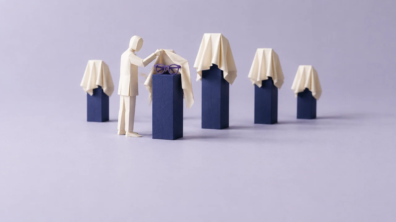 A figure pulls a cloth off one of five draped plinths, revealing violet glasses, while the other shapes stay covered