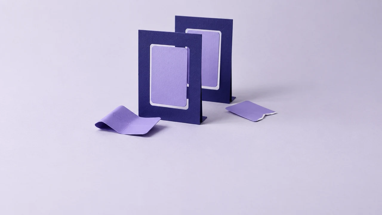 Two upright indigo frames stand one behind the other, a violet card set in each opening, with a bent card and a torn card at their feet