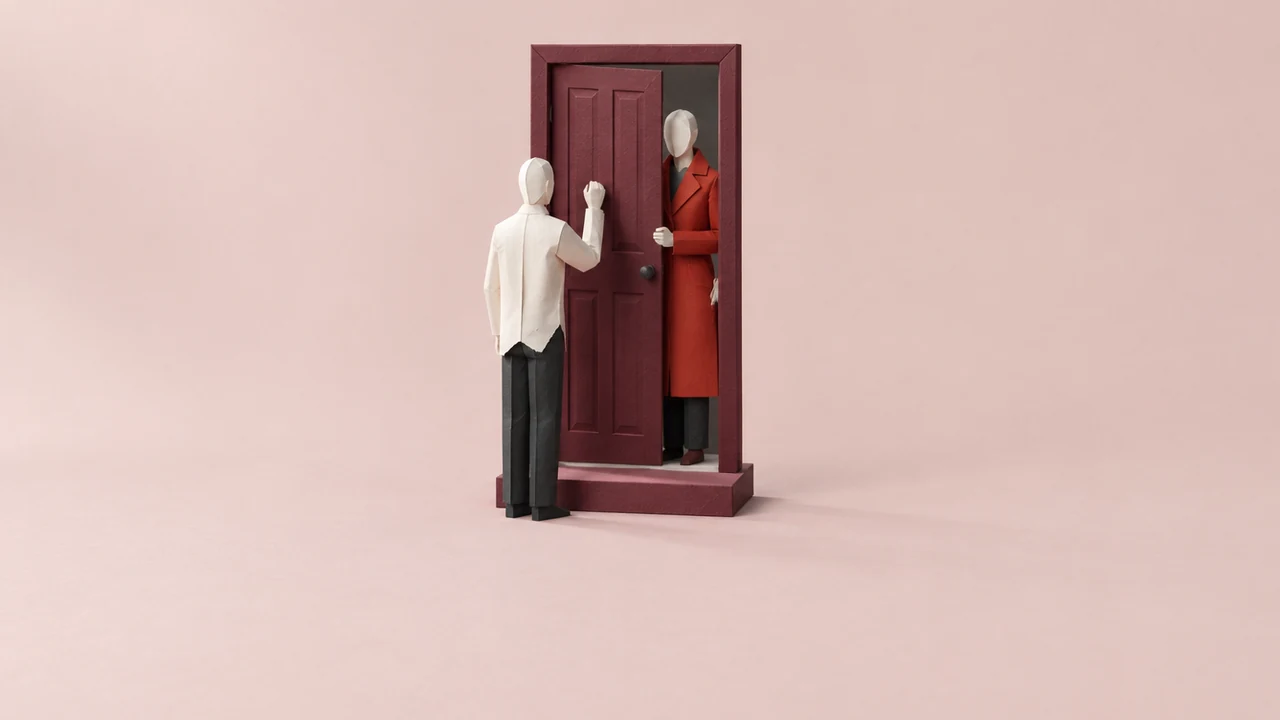In a freestanding doorway, a figure in a fine red coat holds the door while an identical figure in a plain white shirt knocks outside