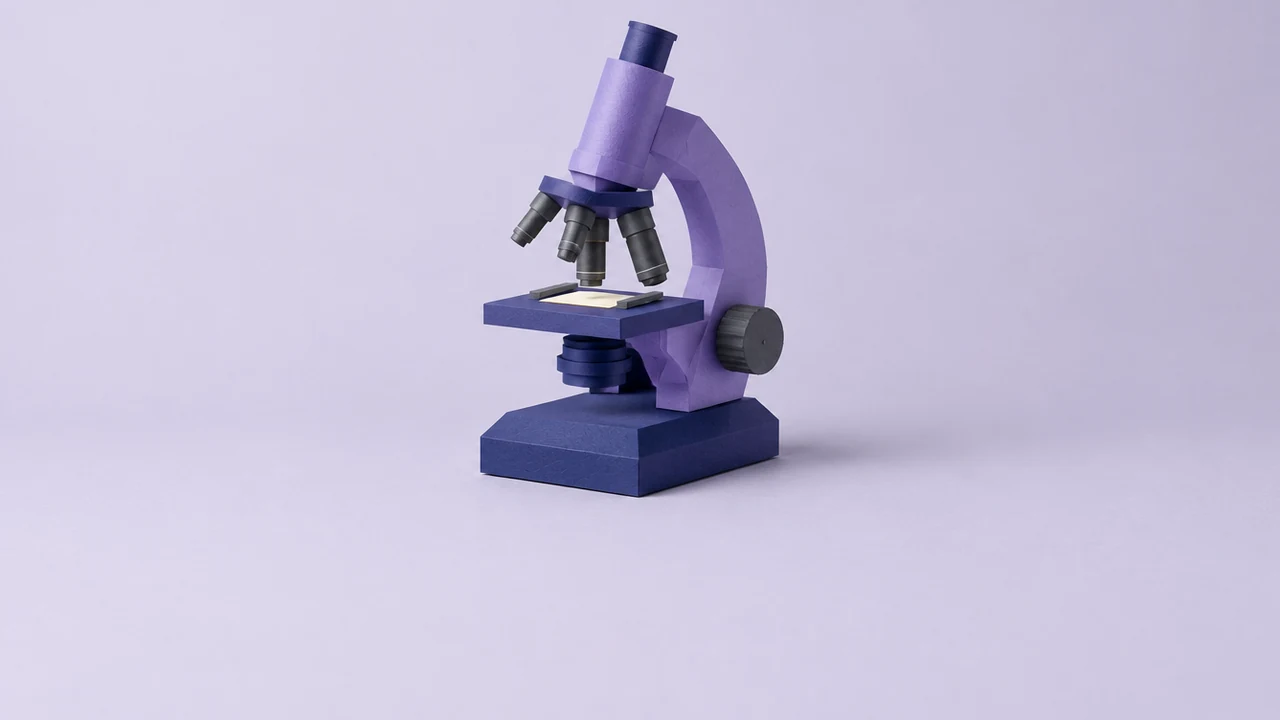 A violet microscope with four objective lenses of different lengths, a medium one turned into place above a plain slide